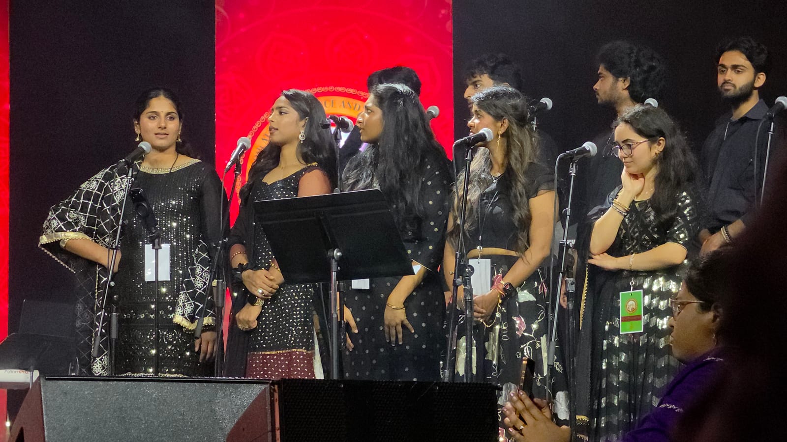 The full line of performers across the stage under red and white light.